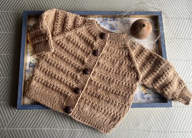 Braune gestrickte Babyjacke mit Raglanärmeln und dunklen Knöpfen
