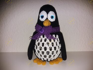 Gehäkelter Pinguin mit lila Schal, Netzmuster am Bauch und orangefarbenem Schnabel und Füßen