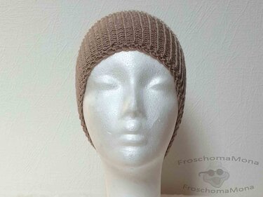 Beige gestrickte Mütze auf weißer Schaufensterpuppe