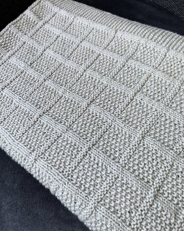 Gestrickte hellbeige Babydecke mit erhabenem Quadratmuster