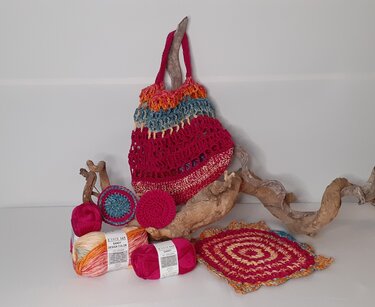 Gehäkelter Beutel, Garnknäuel und Musterproben auf weißem Hintergrund