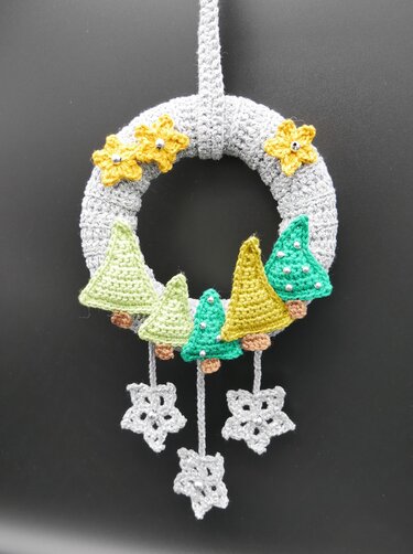 Gehäkelter grauer Türkranz mit fünf Bäumen, gelben Blüten und hängenden Schneeflocken