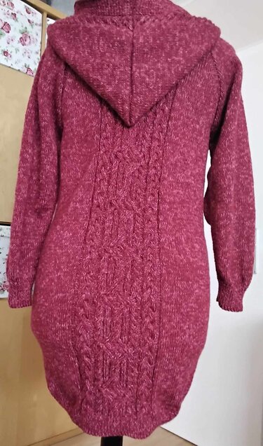 Rückenansicht einer weinroten gestrickten Kapuzenjacke mit mittigem Zopfstrickmuster und gerippten Bündchen