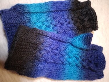 Gestrickte blaue Armstulpen mit Zopfmuster und Daumenöffnung