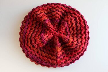 Gehäkelte Baskenmütze in roten und orangefarbenen Tönen, von oben fotografiert