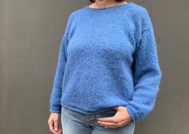 Nahaufnahme eines Oberkörpers in einfachem blauem, glatt gestricktem Pullover mit Rundhalsausschnitt