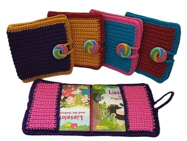 Vier gehäkelte Buchhüllen in verschiedenen Farben mit bunten Knöpfen; eine geöffnet und bestückt mit Kinderbüchern