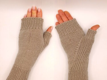 Paar beige gestrickte fingerlose Armstulpen mit Daumenöffnungen auf hellem Hintergrund