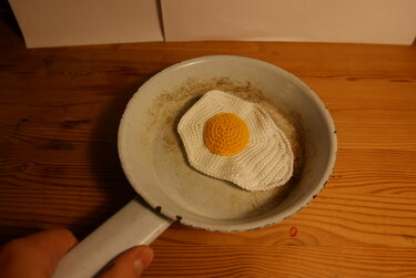 Gehäkeltes Spiegelei, detailreich in einer Bratpfanne präsentiert