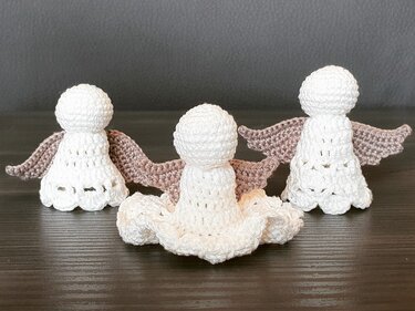 Drei weiße, gehäkelte Amigurumi-Engel mit hellbraunen Flügeln