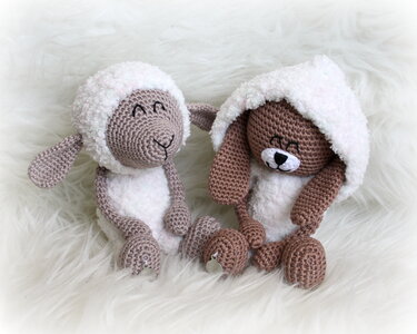 Gehäkeltes Amigurumi-Lamm und Amigurumi-Hase mit flauschigen Körpern auf weißem Fell