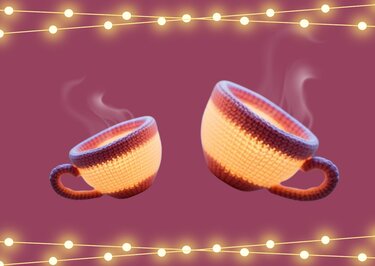 Zwei leuchtende gestreifte gehäkelte Tassen mit Dampfschwaden und Lichterketten auf magentafarbenem Hintergrund