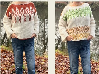 Person in Jeans präsentiert zwei gehäkelte Pullover mit geometrischen Farbmustern vor einem Teich und herbstlichem Laub.