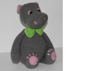 Gehäkeltes graues Nilpferd mit rosa Details und grüner Fliege, sitzend