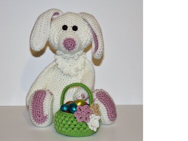 Weißer gehäkelter Amigurumi-Hase mit rosa Ohren und grünem Körbchen