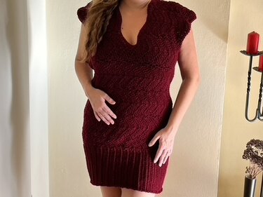 Woman wearing a dark red crochet mini dress with a textured stitch pattern and ribbed hem.