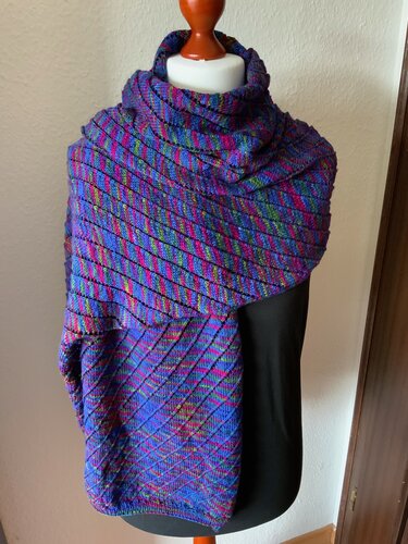 Gestrickter, mehrfarbiger Schal mit diagonalen Streifen in Blau, Pink und Grün auf einer Schneiderpuppe.