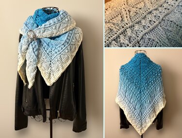 Gehäkeltes Dreieckstuch in Blau‑Creme mit Loch- und Strukturmuster, drapiert auf Schaufensterpuppe mit Spange