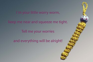 Yellow crocheted worry worm keychain with smiling bead head and attachment loop on a gray background with overlayed poem text.