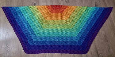 V-förmiges gehäkeltes Tuch mit Regenbogenfarbverlauf auf Holzboden