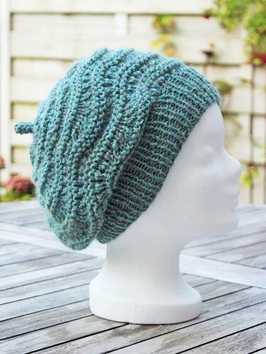 Teal textured knitted slouchy beanie on white mannequin head, side view
