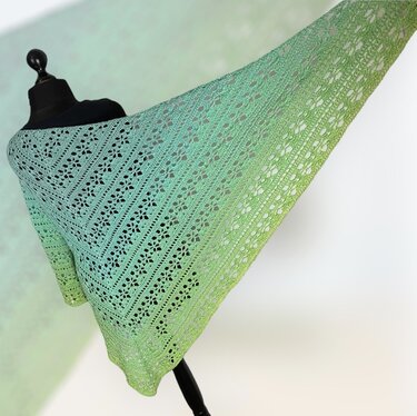 Green ombré crochet triangle shawl with openwork lace draped on a mannequin.