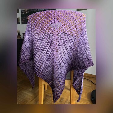 Lila verlaufendes gehäkeltes Dreieckstuch mit offenem Lochmuster, über einem Stuhl drapiert