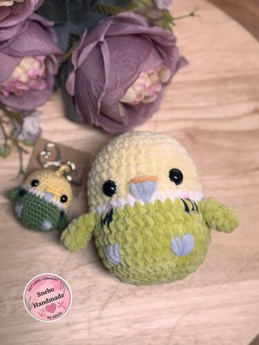 Kleiner und großer gehäkelter Wellensittich-Amigurumi in Grün und Gelb auf Holztisch mit Mini-Schlüsselanhänger