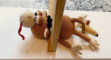 Gehäkelter braun-beigefarbener Amigurumi-Affe mit roter Zunge als Türstopper
