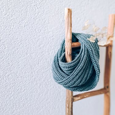 Petrolfarbener gehäkelter Loop mit Rippenmuster an einer Holzleiter