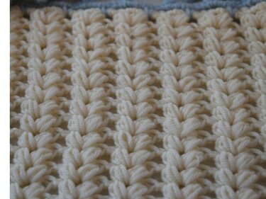 Gehäkeltes Textil in Creme mit Noppenmuster und blauem Rand