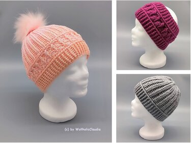 Drei gehäkelte Kopfbedeckungen auf weißen Schaufensterköpfen: eine zartrosa Mütze mit Bommel, ein magentafarbenes Stirnband und eine graue Beanie.