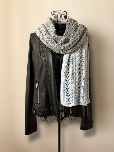 Light gray lacy crochet scarf wrapped around a wire mannequin wearing a black leather jacket
