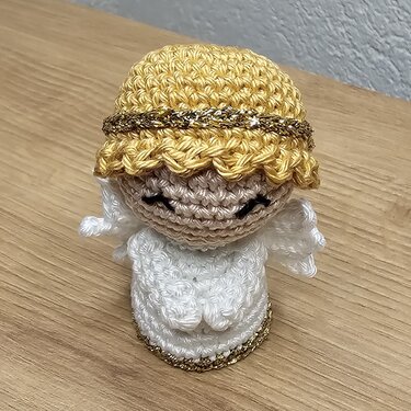 Gehäkeltes Engelchen-Amigurumi in Weiß mit goldenen Haaren, kleinen Flügeln und geschlossenen Augen