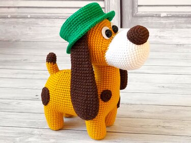 Amigurumi dog toy, yellow-orange with brown spots and a green hat