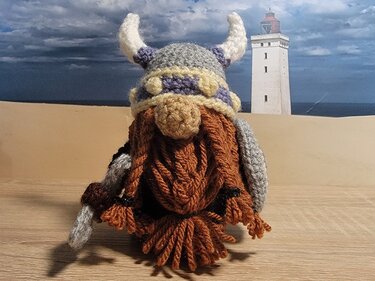 Gehäkelter Wikingernickel mit Hornhelm und braunem Bart vor Leuchtturm-Kulisse