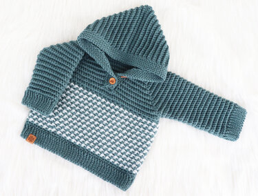 Crocheted baby hooded sweater in teal and white with textured midsection, laid flat on a white background.