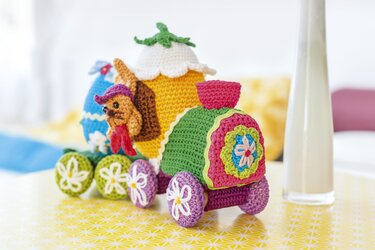 Bunter gehäkelter Deko-Zug mit Osterei-Wagen, kleiner Tierfigur und blütenverzierten Rädern
