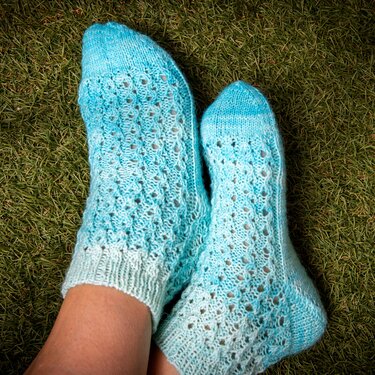 Helltürkise gestrickte Knöchelsocken mit Lochmuster auf Gras
