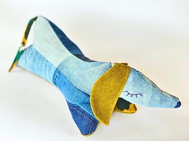 Genähtes Dackelkissen aus Jeanspatchwork mit gelben Ohren und gesticktem Augenmotiv