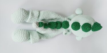 Mintgrüner gehäkelter Amigurumi-Drache von oben mit dunklen, runden Rückenschuppen