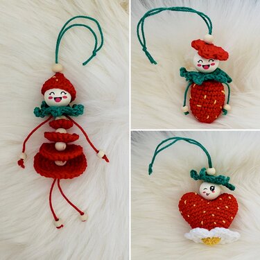 Drei gehäkelte Anhänger: ein Püppchen, eine Erdbeere und ein Herz, mit Holzperlenköpfen auf hellem Hintergrund.