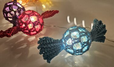 Lichterkette mit gehäkelten Bonbon-Hüllen in Blau, Rot und Lila