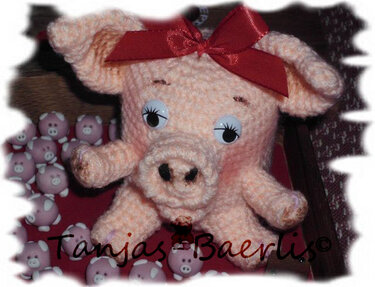 Handgehäkeltes rosa Schweinchen mit roter Schleife und großen Augen