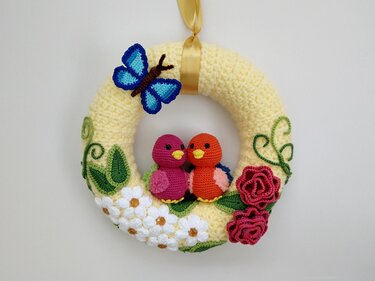 Gehäkelter gelber Türkranz mit zwei Vögeln, blauem Schmetterling und Blumenapplikationen