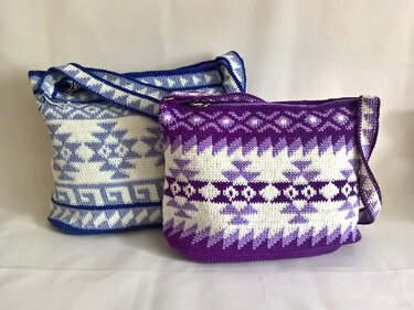 Zwei gehäkelte Umhängetaschen in Blau-Weiß und Lila-Weiß mit geometrischem Ethno-Muster und Reißverschluss.