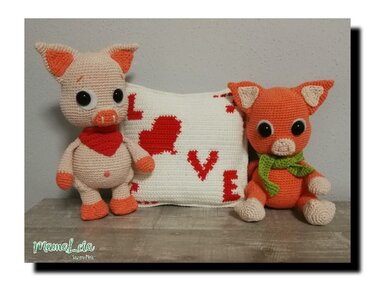 Gehäkeltes Schwein und Fuchs vor weißem Kissen mit roten Herzen und dem Schriftzug LOVE