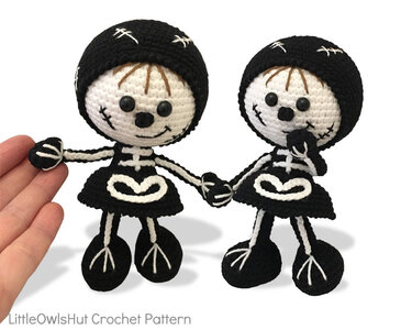 Two black and white crochet skeleton dolls holding hands