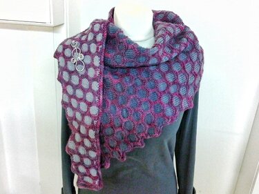 Gestricktes lila-graues Dreieckstuch mit Wabenmuster auf Schaufensterpuppe, mit Schalspange