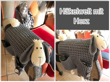 Gehäkelter Armlehnen-Utensilo in Schafsform mit Taschen für Fernbedienung und Brille an einem Sessel.